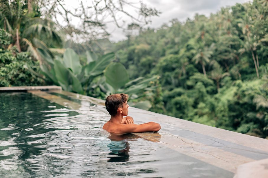 Guest relaxing in an infinity pool overlooking Bali jungle